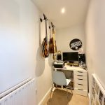Small home office with guitars and computer desk.