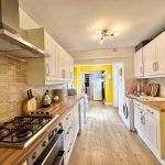Modern kitchen with wooden counters and white cabinets.