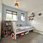 Children's bedroom with bed, bookshelves, and toys.