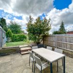 Garden with patio table, chairs, and vibrant greenery.