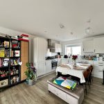 Modern kitchen with dining table and bookshelf.