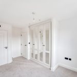 Empty white room with mirrored wardrobe and doors.