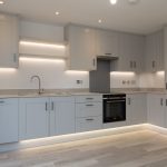 Modern grey kitchen design with under-cabinet lighting.