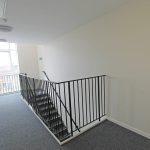 Bright corridor with staircase and window view.