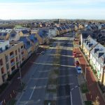 Aerial view of solar-roofed terraced houses and road.