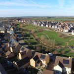 Aerial view of suburban houses and green spaces.