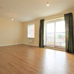 Spacious living room with wooden floor and balcony.