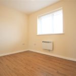 Empty room with wooden flooring and window.
