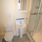 Compact bathroom with shower, sink, and toilet.