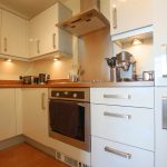 Modern kitchen with white cabinets and appliances.