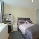 Modern bedroom with double bed and shoe rack.