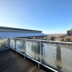 Balcony overlooking industrial buildings, clear blue sky.