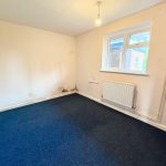 Empty room with blue carpet, white walls, window.
