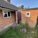 Side view of brick house with garden flowers.