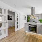Modern kitchen with sliding doors and wooden flooring.