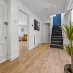 Bright hallway with wooden flooring and staircase.