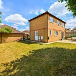 Sunny suburban garden with patio and BBQ grill.