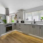 Modern kitchen with grey cabinets and wood flooring.