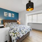 Cosy bedroom with floral bedding and blue wall.