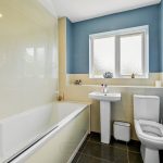 Modern bathroom with blue walls and white fixtures.