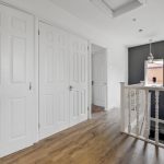 Bright hallway with wooden flooring and white doors.