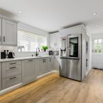 Modern kitchen with grey cabinets and wooden flooring.