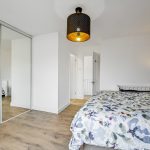 Modern bedroom with mirrored wardrobe and floral bedding.