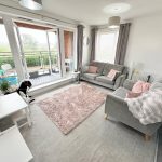 Modern living room with balcony and grey sofas.