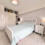 Cosy bedroom with desk and white furniture.