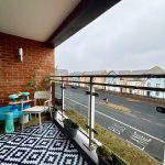 Modern balcony overlooking street with houses.