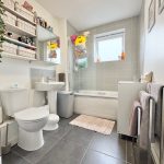 Modern bathroom with grey tiles and shelving.