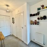 White hallway with shelves of figurines and door.