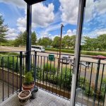 Balcony view with cars and trees outside.