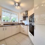 Modern kitchen with white cabinets and appliances.