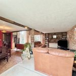 Spacious living room with brick walls and leather sofas.
