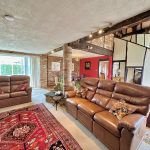 Spacious living room with leather sofas and rugs.