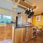 Cosy kitchen with hanging pans and wooden cabinets.