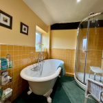 Cosy bathroom, freestanding tub, and curved shower.