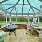 Sunny conservatory with seating and art table.
