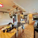 Cosy kitchen with wooden cabinets and hanging utensils.