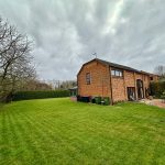 Brick house with large green garden and patio.