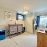 Compact bedroom with fold-up bed and blue curtains.
