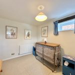 Small bedroom with folded cot and artworks.