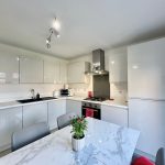 Modern kitchen with white cabinets and dining table.