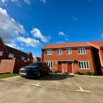 Red-brick house with parked black car