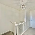 Bright hallway with white staircase and modern light fixture.