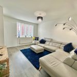 Modern living room with beige leather sofa and lamp.