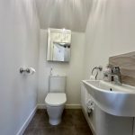 Small modern white bathroom with sink and toilet.