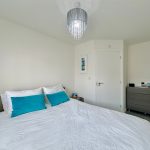 Modern bedroom with bed, dresser, and chandelier.