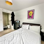 Modern bedroom with ensuite bathroom and vibrant artwork.